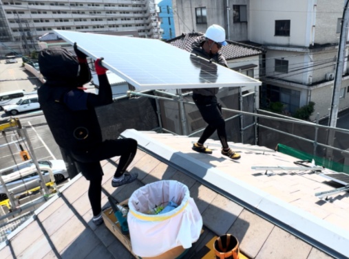 太陽光パネルを持ち上げる現場作業風景