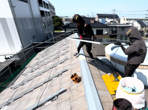 屋根の上で太陽光パネルを運ぶスタッフのファーストビュー写真